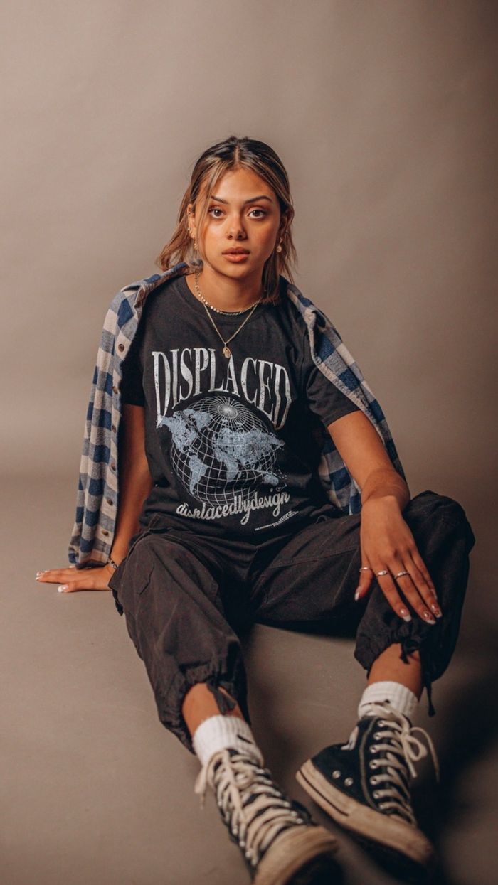 Young Hispanic woman modeling a cool graphic tee with sneakers, exuding urban fashion style.