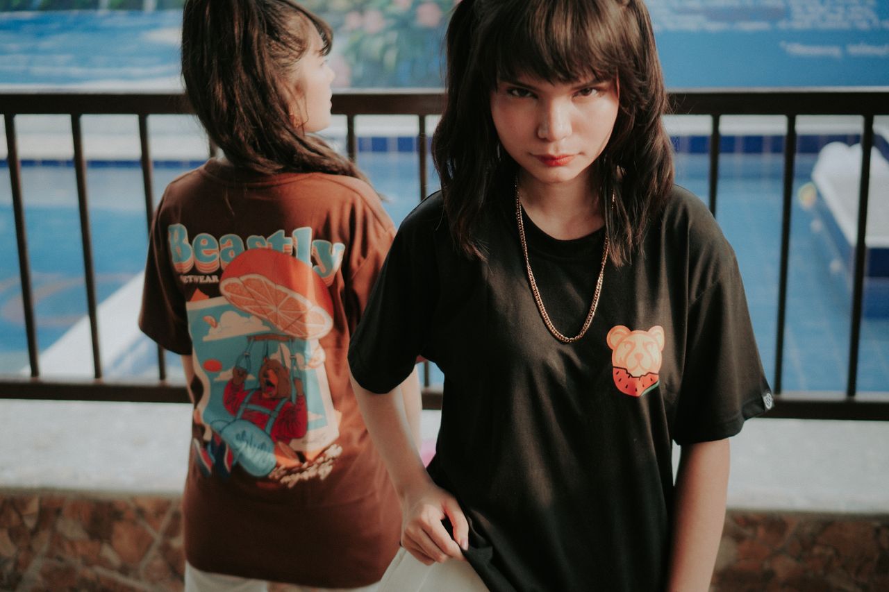 Two young women in trendy streetwear standing by a pool. Explore style and attitude.